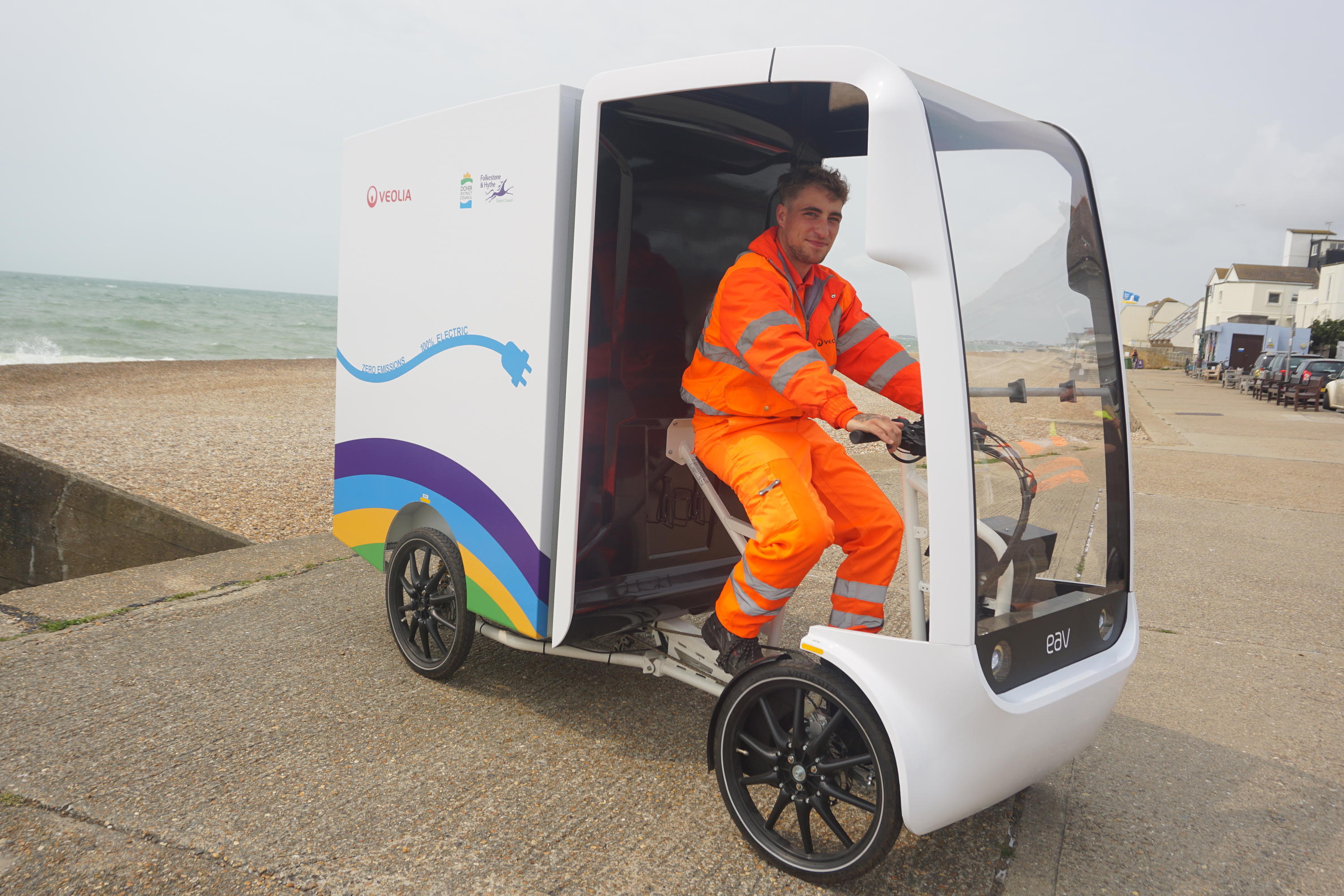 An operative drives an e-bike on the seafront.